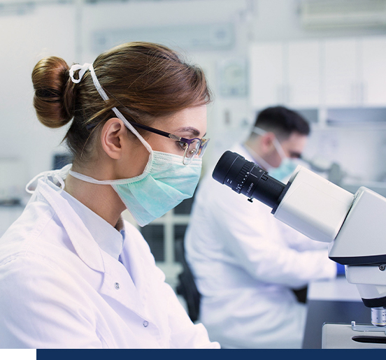 A female scientist is looking into a microscope.