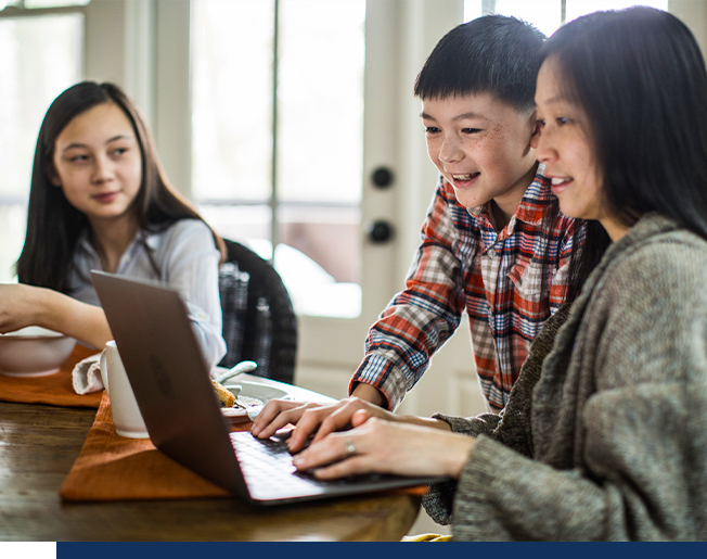 A woman looking at her computer with her two kids