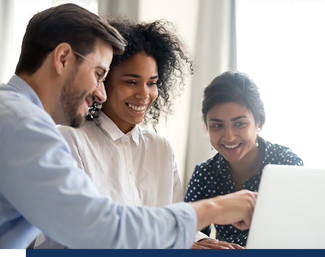 Three employees looking at screen and smiling.