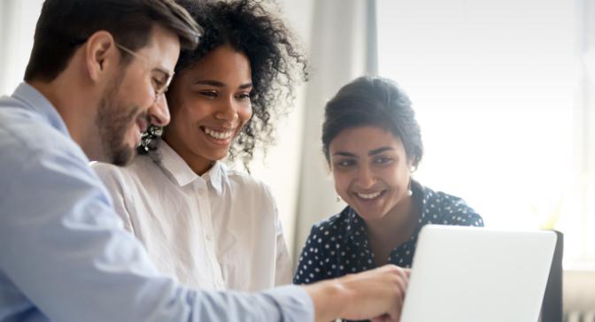 Three employees looking at screen and smiling.